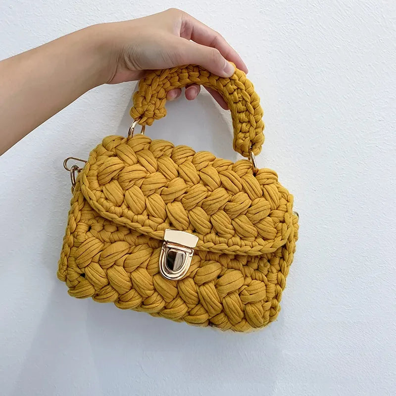Yellow woven handbag held by a hand on a white background