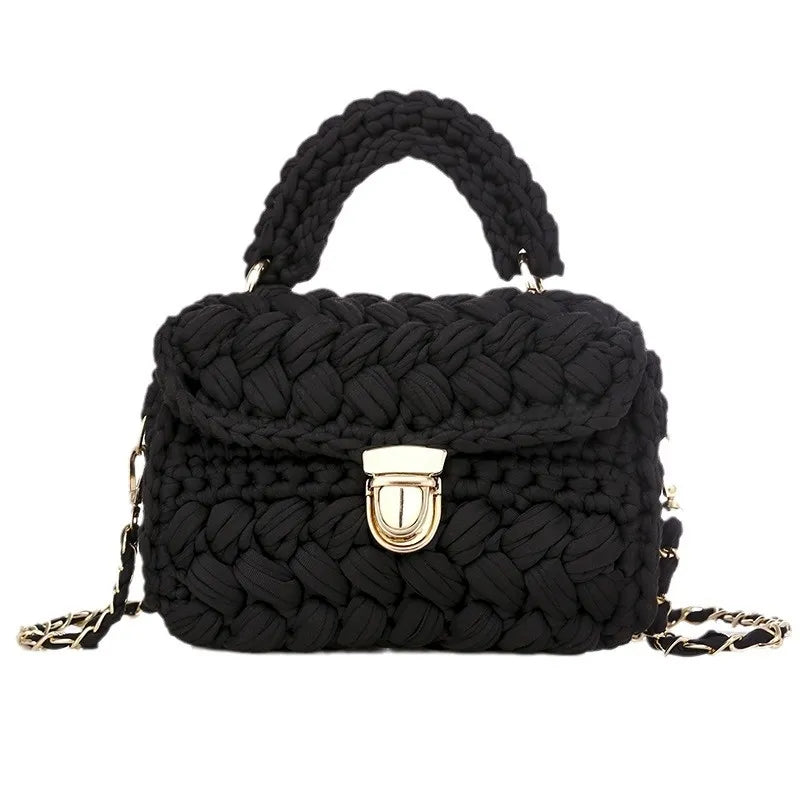 Black woven handbag with a gold clasp on a white background